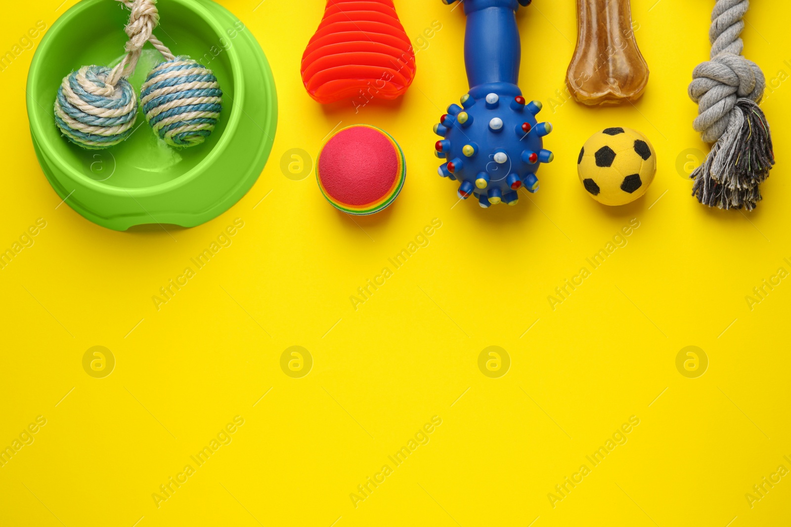 Photo of Flat lay composition with pet toys and feeding bowl on yellow background, space for text