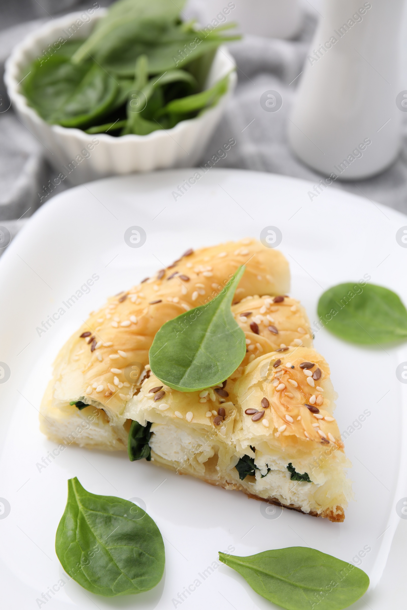 Photo of Piece of delicious puff pastry with spinach on light table, closeup