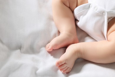Photo of Little baby in bodysuit on bed, closeup. Space for text