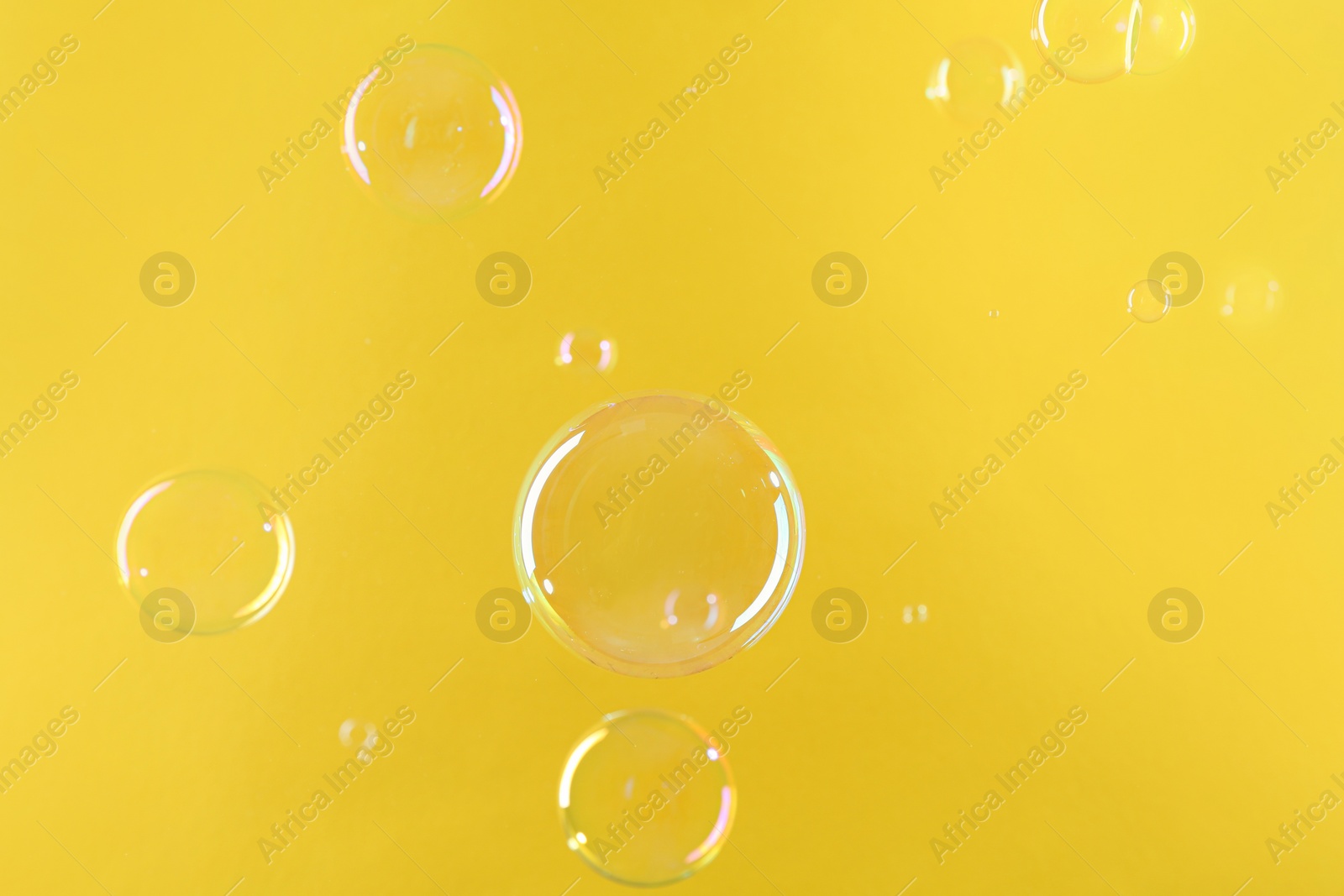 Photo of Beautiful transparent soap bubbles on yellow background