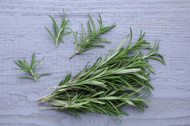 Photo of Sprigs of fresh rosemary on wooden table, flat lay