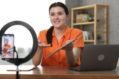 Photo of Smiling technology blogger with tablets recording video review at home
