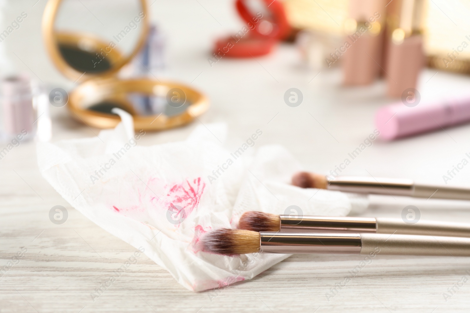 Photo of Dirty wet wipe and brushes on white wooden table, closeup