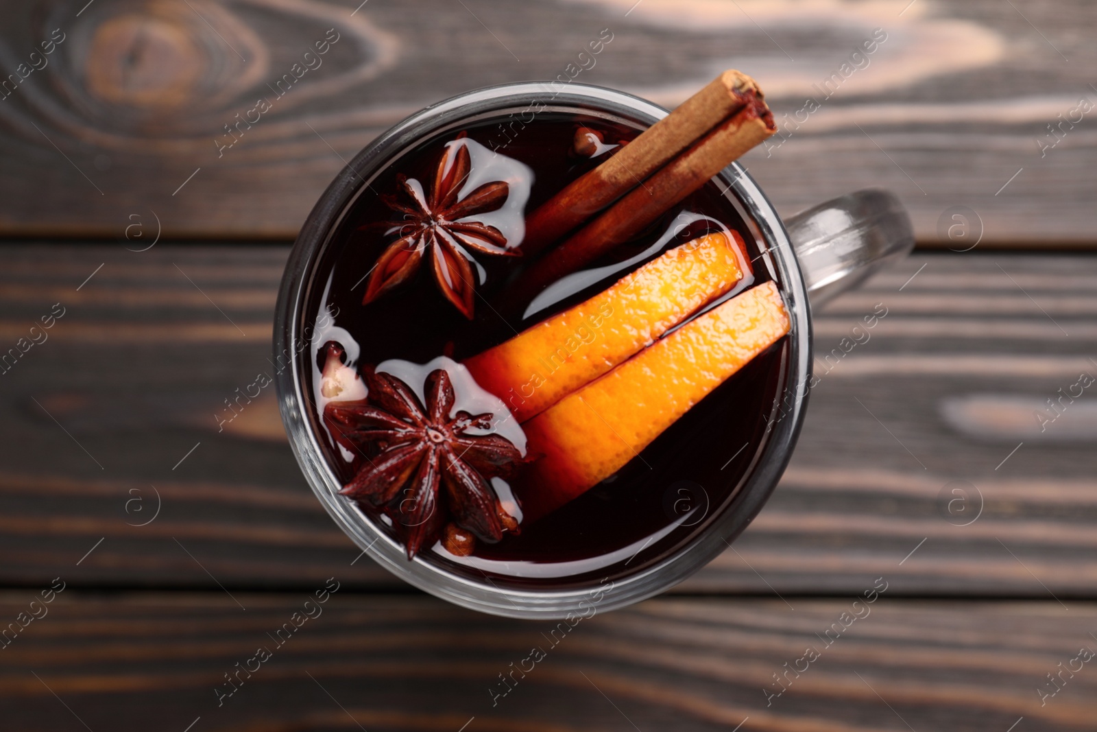Photo of Cup with mulled wine on wooden table, top view