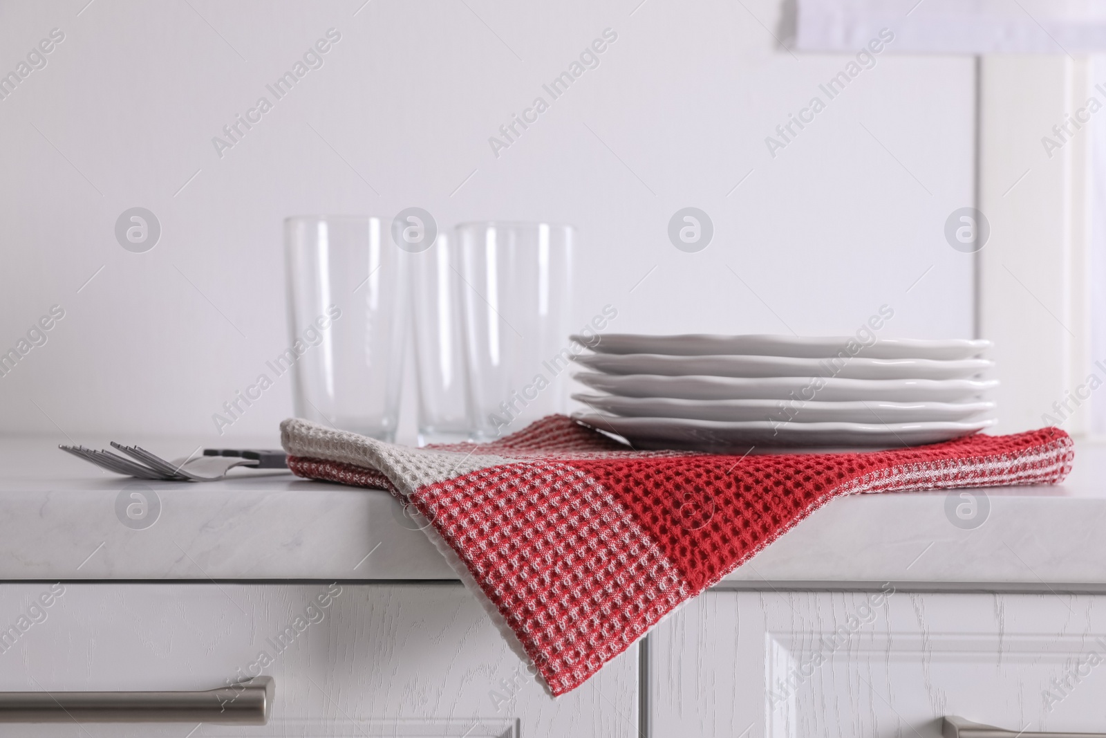 Photo of Dry kitchen towel and clean dishware on white marble countertop