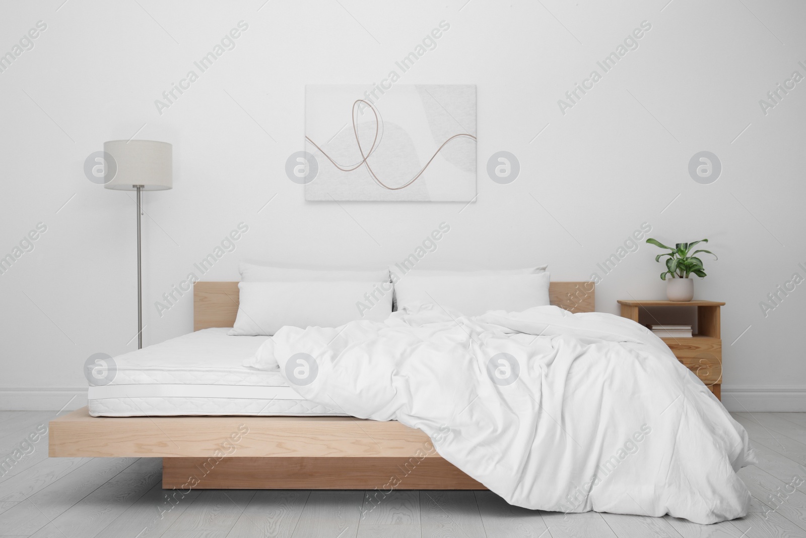 Photo of Wooden bed with soft white mattress, blanket and pillows in cozy room interior