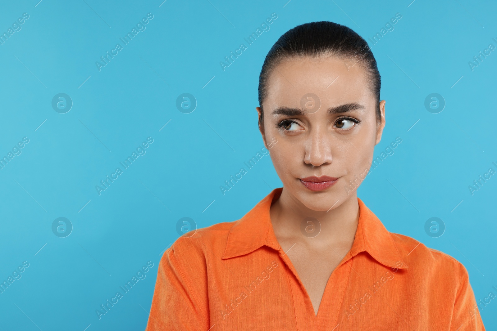 Photo of Portrait of resentful woman on light blue background. Space for text