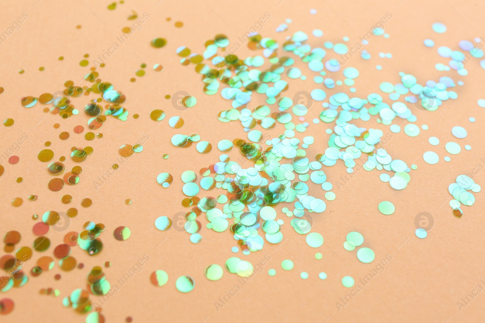 Photo of Shiny bright glitter scattered on beige background