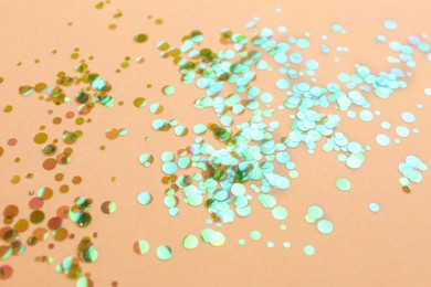 Photo of Shiny bright glitter scattered on beige background