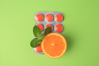 Fresh orange, mint leaves and blister with cough drops on light green background, flat lay