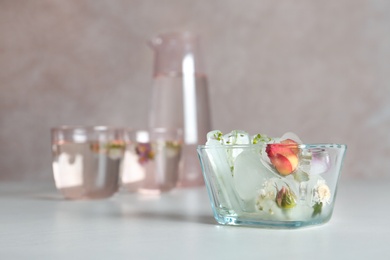 Bowl with floral ice cubes on table. Space for text