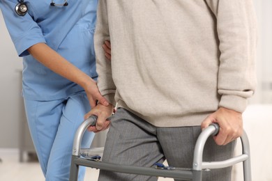 Photo of Nurse helping elderly patient with walker indoors, closeup