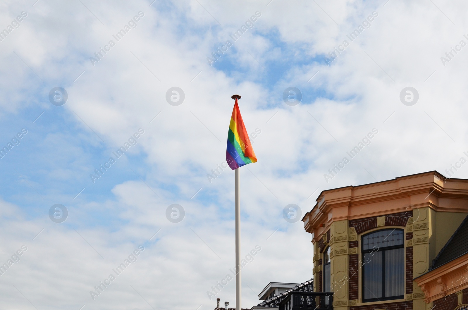 Photo of Bright rainbow LGBT flag against blue sky