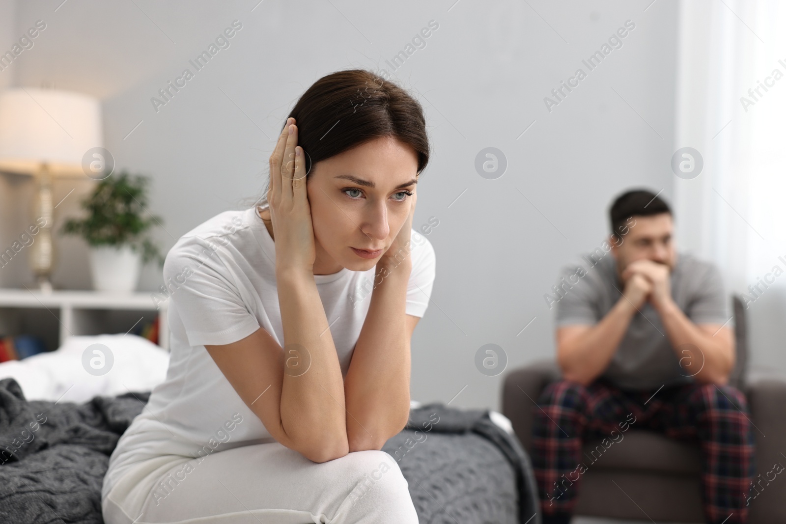 Photo of Offended couple ignoring each other after quarrel in bedroom, selective focus. Relationship problems