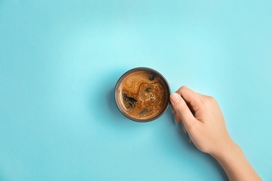 Photo of Young woman with cup of delicious hot coffee on color background, top view