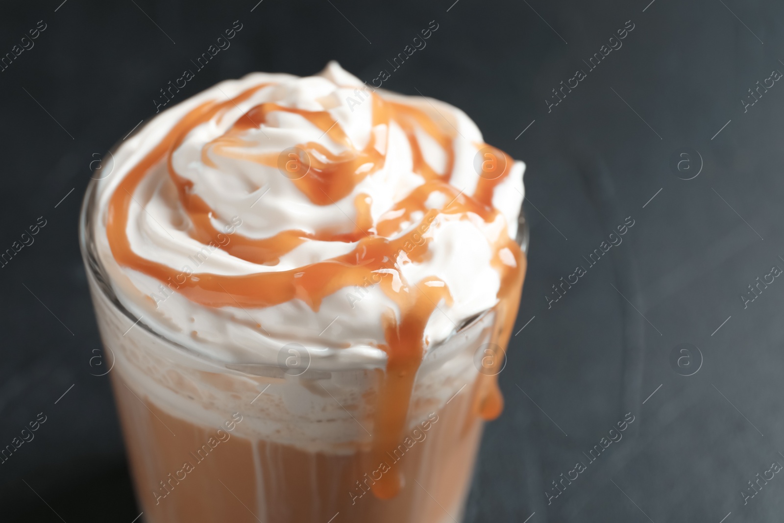 Photo of Glass with delicious caramel frappe on grey background, closeup