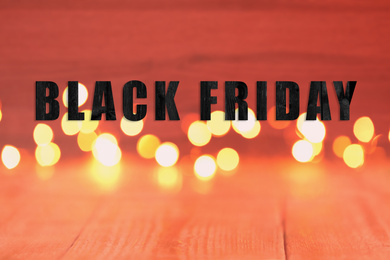 Image of Phrase Black Friday and blurred view of beautiful lights on background 