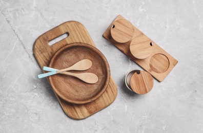 Wooden cooking utensils on grey marble table, flat lay