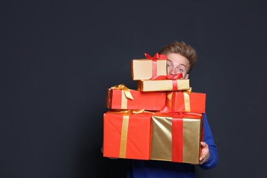 Photo of Young man with Christmas gifts on dark background. Space for text