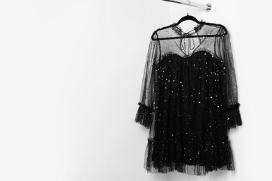 Photo of Beautiful black women's party dress on hanger, space for text. Stylish trendy clothes for high school prom