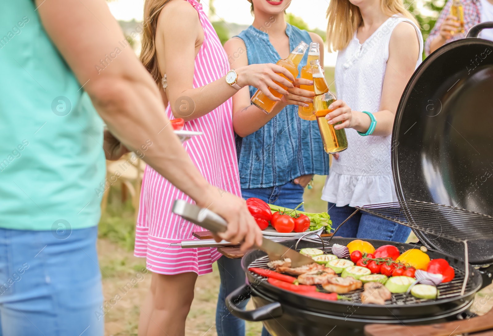 Photo of Young people having barbecue with modern grill outdoors