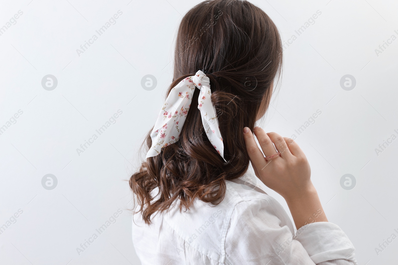 Photo of Young woman with stylish bandana on light background, back view