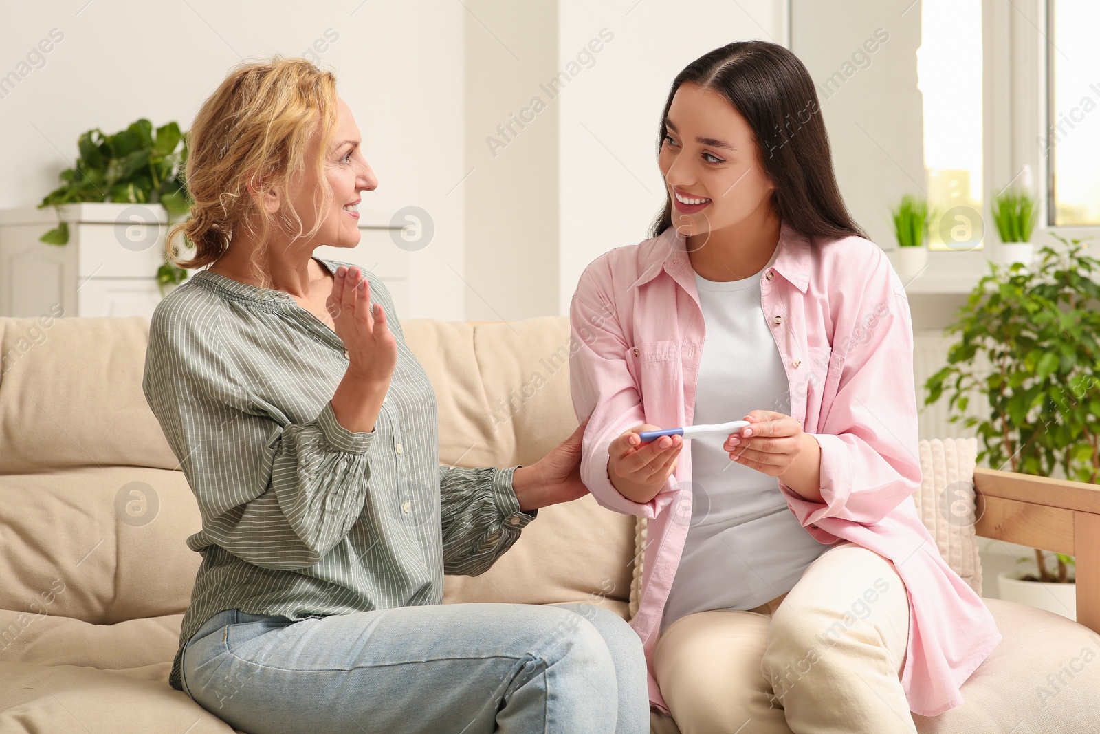 Photo of Happy pregnant woman spending time with her mother at home. Grandparents' reaction to future grandson