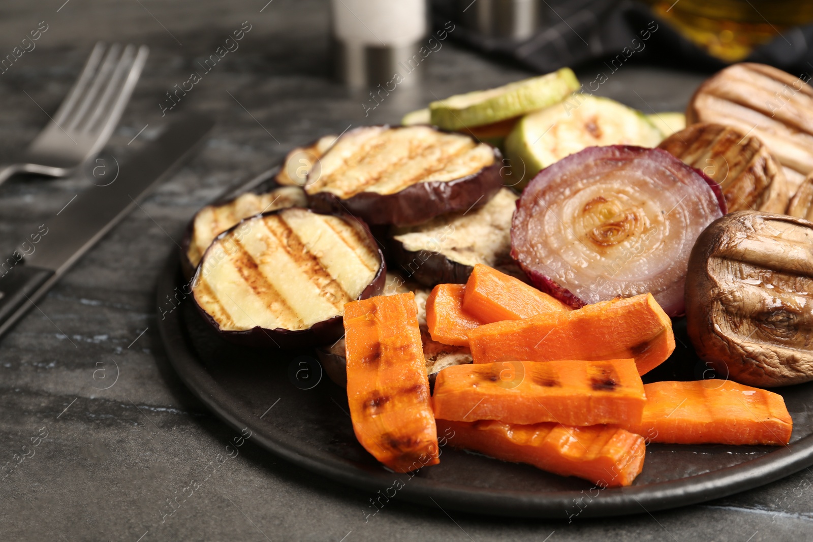 Photo of Delicious grilled vegetables and mushrooms served on grey table, closeup