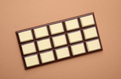 Photo of Tasty chocolate bar on brown background, top view