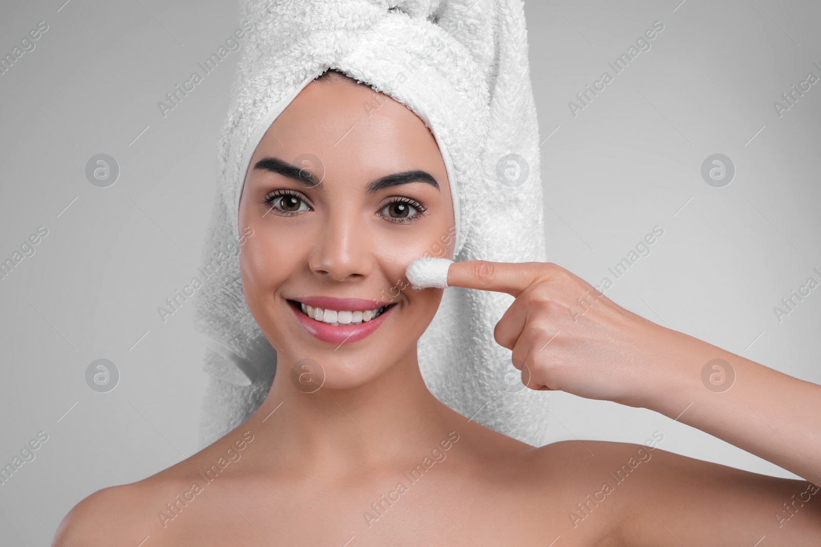 Photo of Woman using silkworm cocoon in skin care routine on light grey background