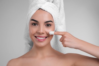 Photo of Woman using silkworm cocoon in skin care routine on light grey background