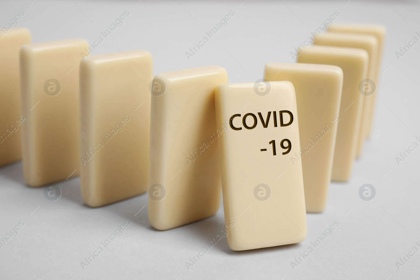 Photo of Domino tiles on light grey background, closeup. Spreading of coronavirus concept