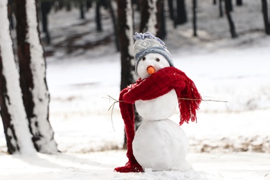 Funny snowman with scarf and hat in winter forest