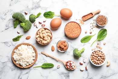 Photo of Set of natural food high in protein on marble background, top view