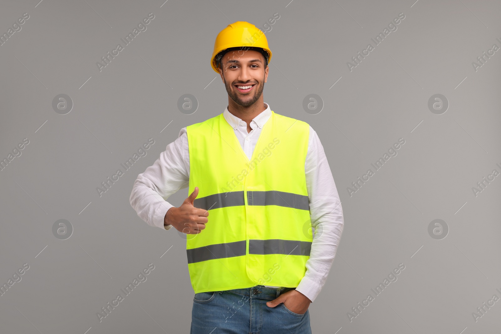 Photo of Engineer in hard hat showing thumb up on grey background