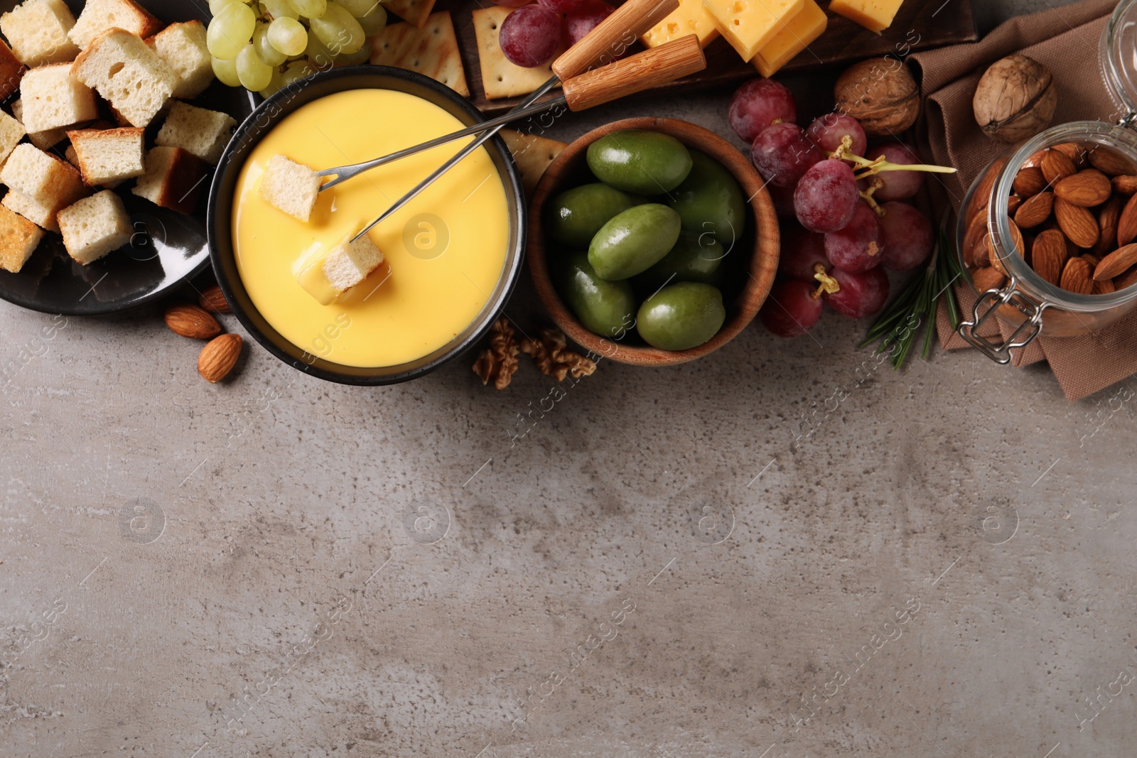 Photo of Tasty cheese fondue and snacks on grey table, flat lay. Space for text