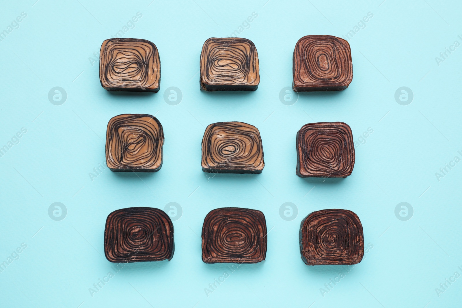 Photo of Tasty chocolate candies on light blue background, flat lay