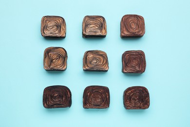 Tasty chocolate candies on light blue background, flat lay