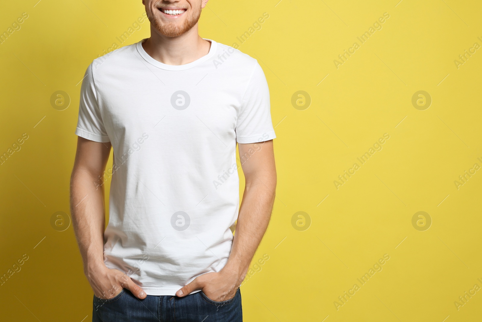 Photo of Young man wearing blank t-shirt on yellow background, closeup. Mockup for design