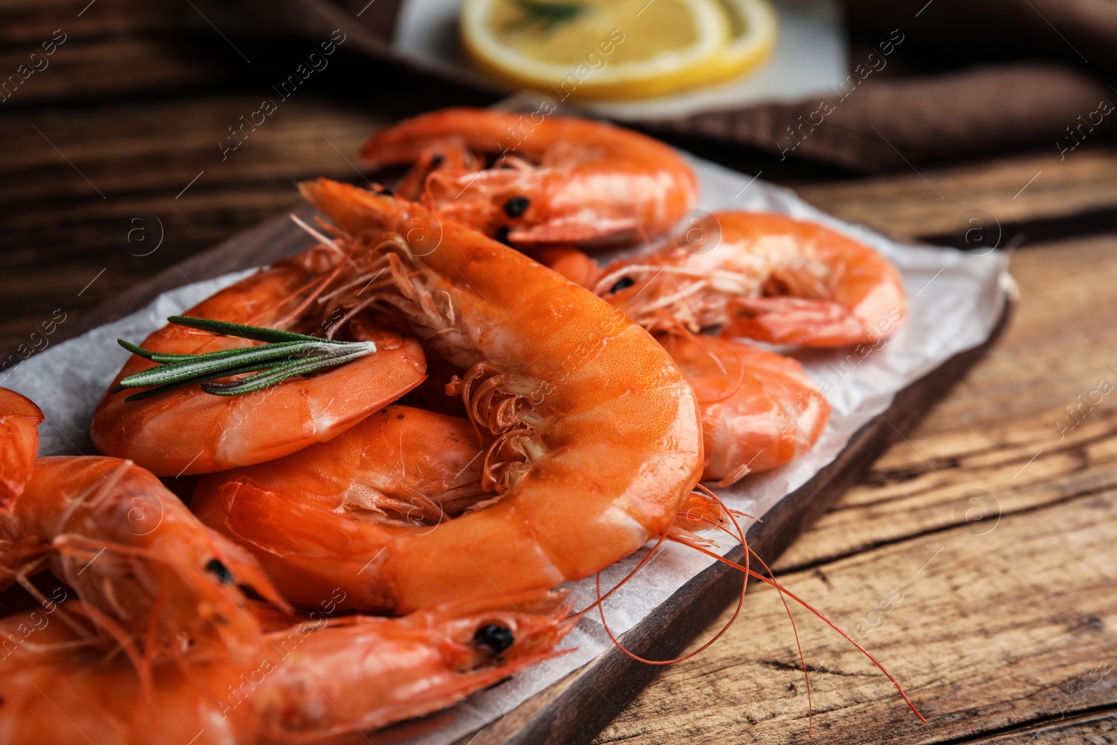 Photo of Delicious cooked shrimps with rosemary on wooden table, closeup