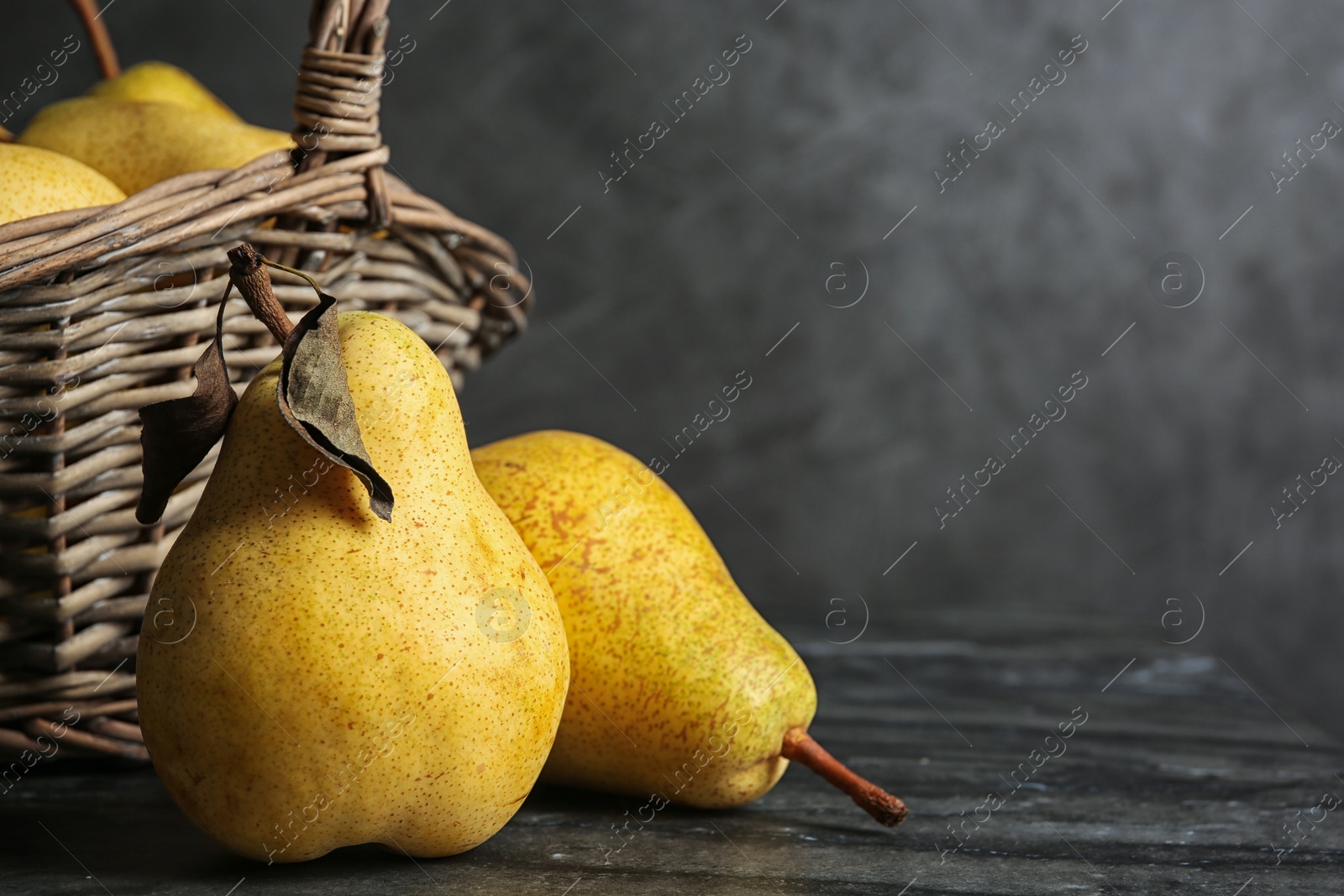 Photo of Basket of fresh ripe pears on table against gray background with space for text