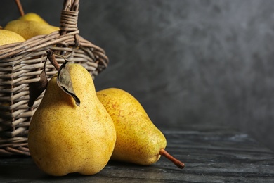 Photo of Basket of fresh ripe pears on table against gray background with space for text