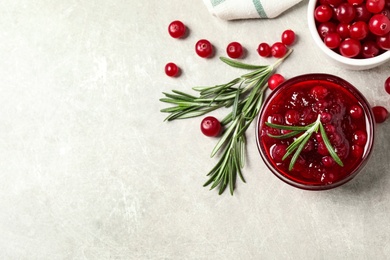 Cranberry sauce, rosemary and fresh berries on light table, flat lay. Space for text