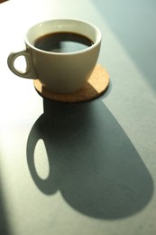 Cup of delicious coffee on grey table