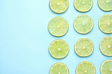 Photo of Fresh juicy lime slices on light blue background, flat lay. Space for text