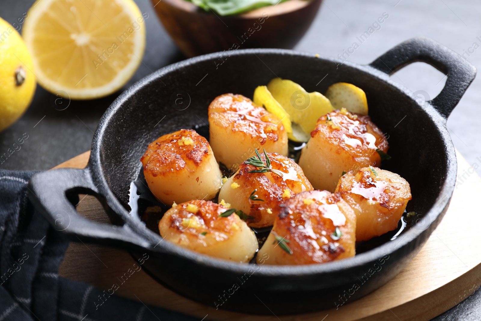 Photo of Delicious fried scallops and lemons on gray table, closeup