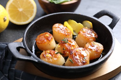 Photo of Delicious fried scallops and lemons on gray table, closeup