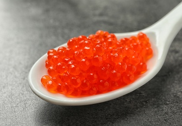 Photo of Spoon with delicious red caviar on grey background