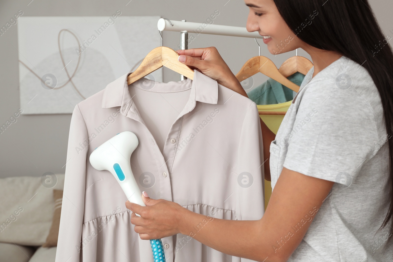 Photo of Woman steaming blouse on hanger at home, closeup