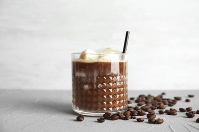 Coffee drink with milk ice cubes and beans on table against light background